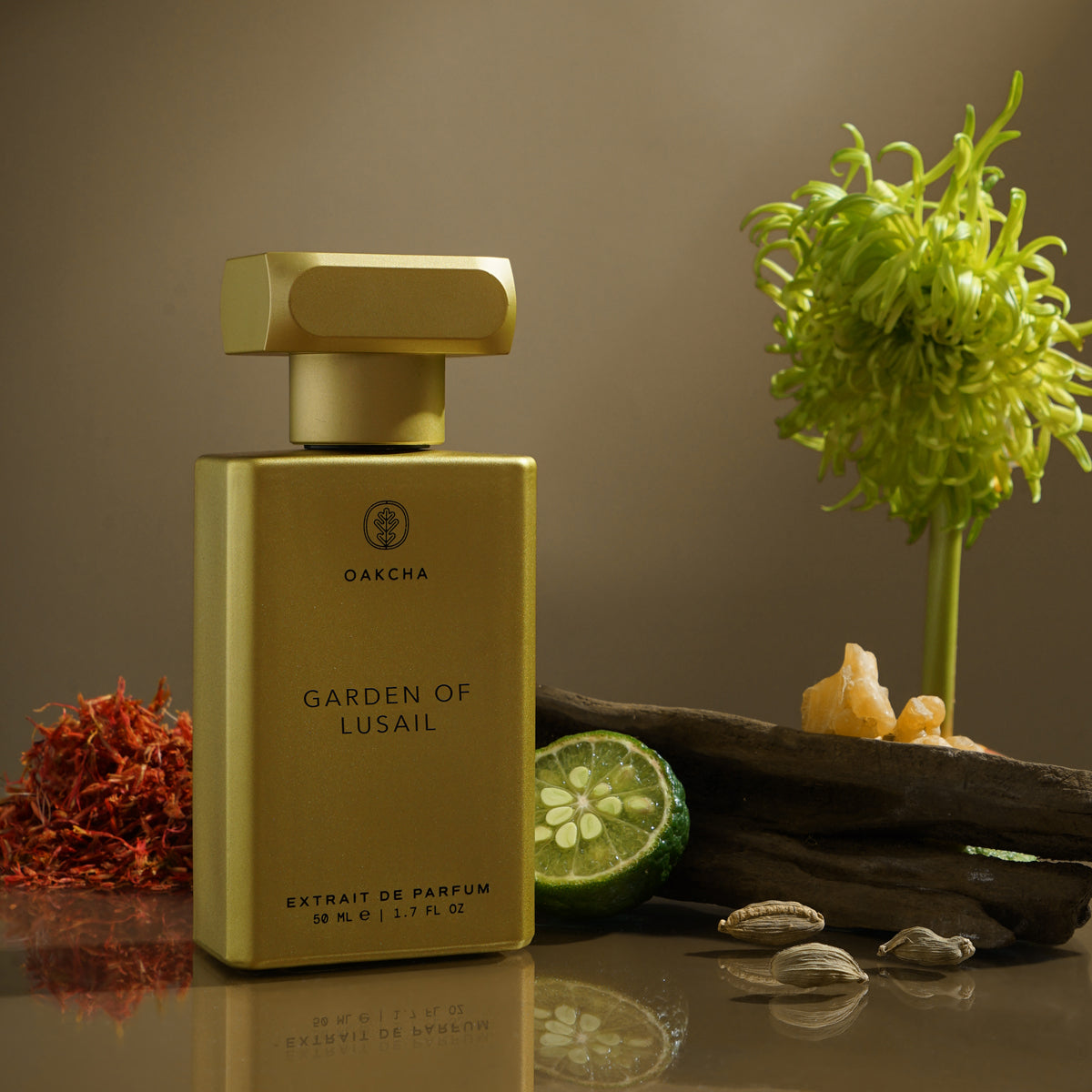 Front view of Garden of Lusail perfume bottle showing gold rectangular bottle and cap on reflective tabletop with herbs