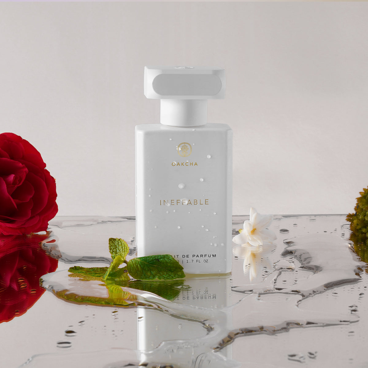 Front view of Ineffable bottle showcasing white rectangular bottle with gold logo on marble surface and red rose