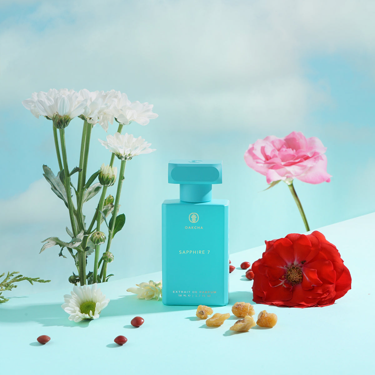 Front view of Sapphire 7 perfume bottle showing turquoise bottle and cap with scattered flowers on a light blue background