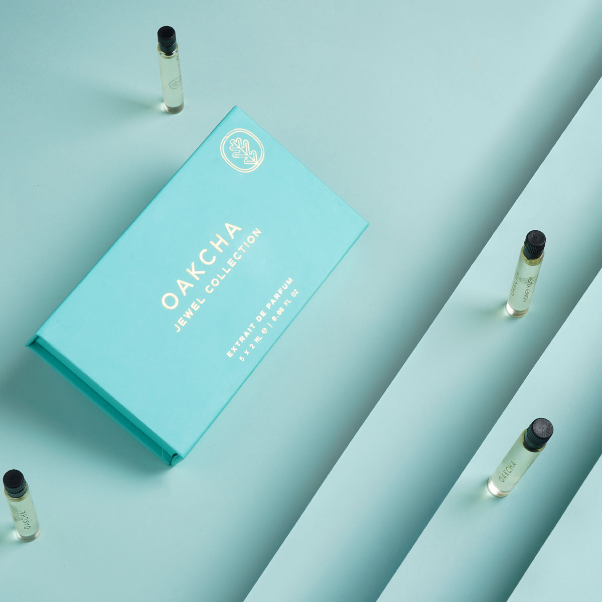 Angled view of turquoise Jewel Sample Set box with four visible perfume sample vials on a mint background