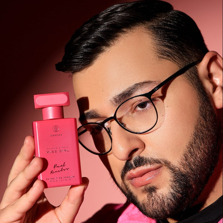 Front view of pink Miss Girl perfume bottle showcasing the Oakcha and Paul Reactss label, held by a man with glasses