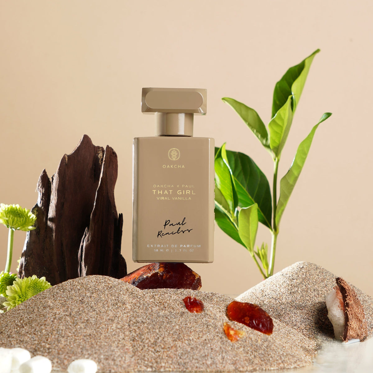 Front view of That Girl Viral Vanilla perfume bottle on sand with gold cap, green leaf, and amber accents